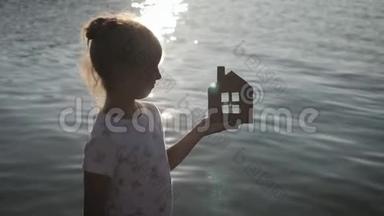 日落时，女孩在海滩上拿着纸房子。 人，<strong>梦</strong>想，家庭，房地产和家居理念.. 儿<strong>童梦</strong>